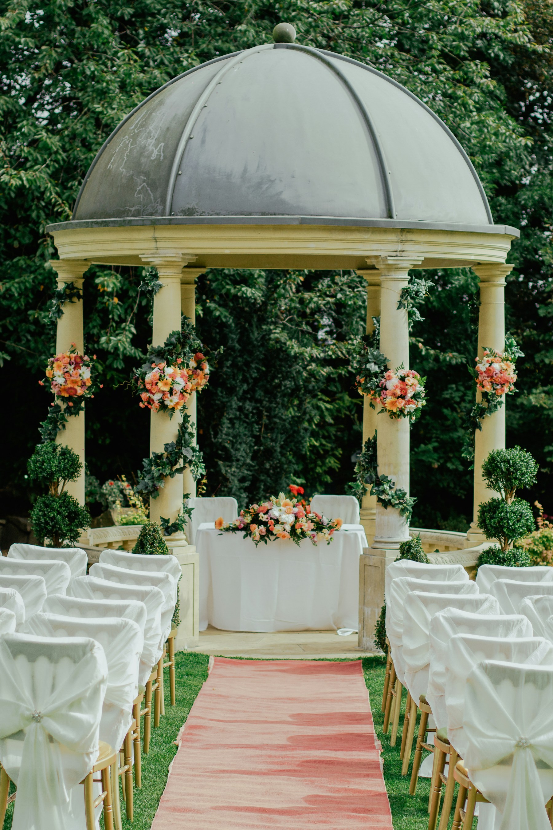 Garden ceremony decorated with soft coral and cream floral arrangements